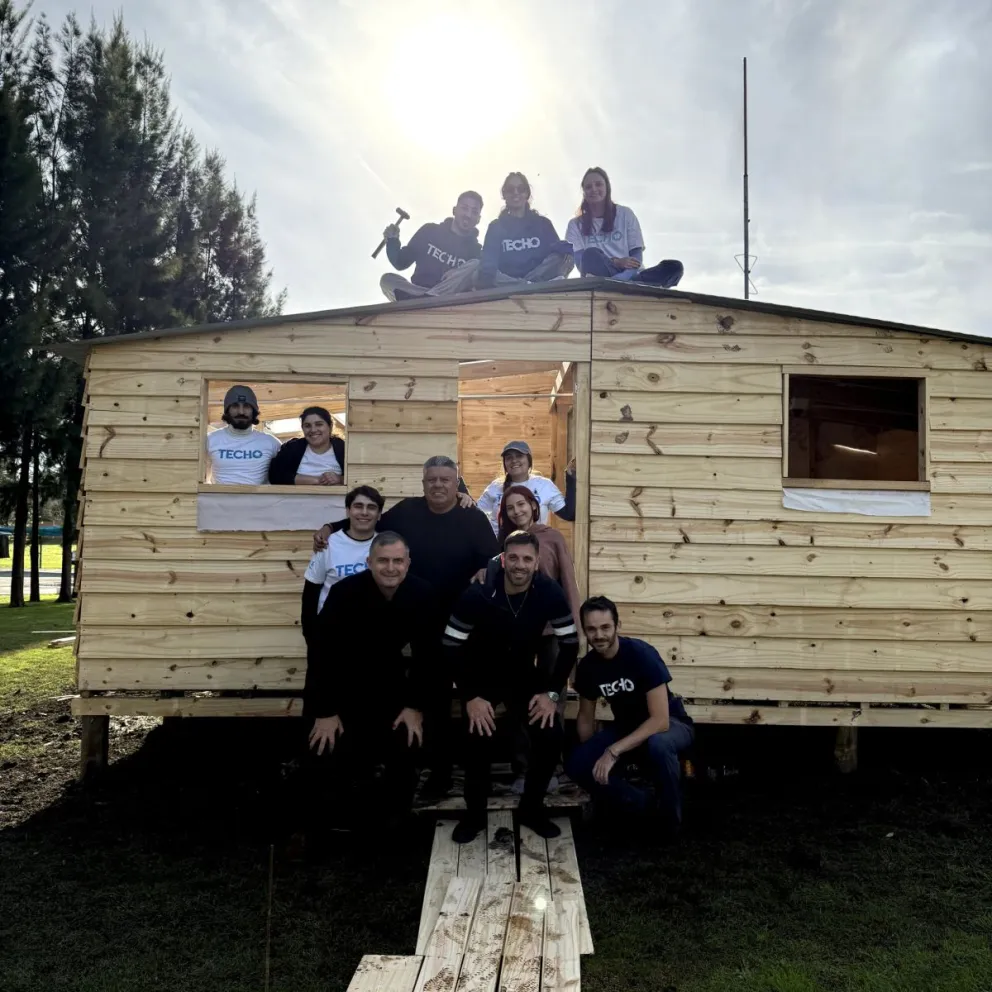 Wiski. Tapia junto a los integrantes de la ONG Techo Argentina en la casa modelo de madera que se construyó en Ezeiza y que despertó cuestionamientos.