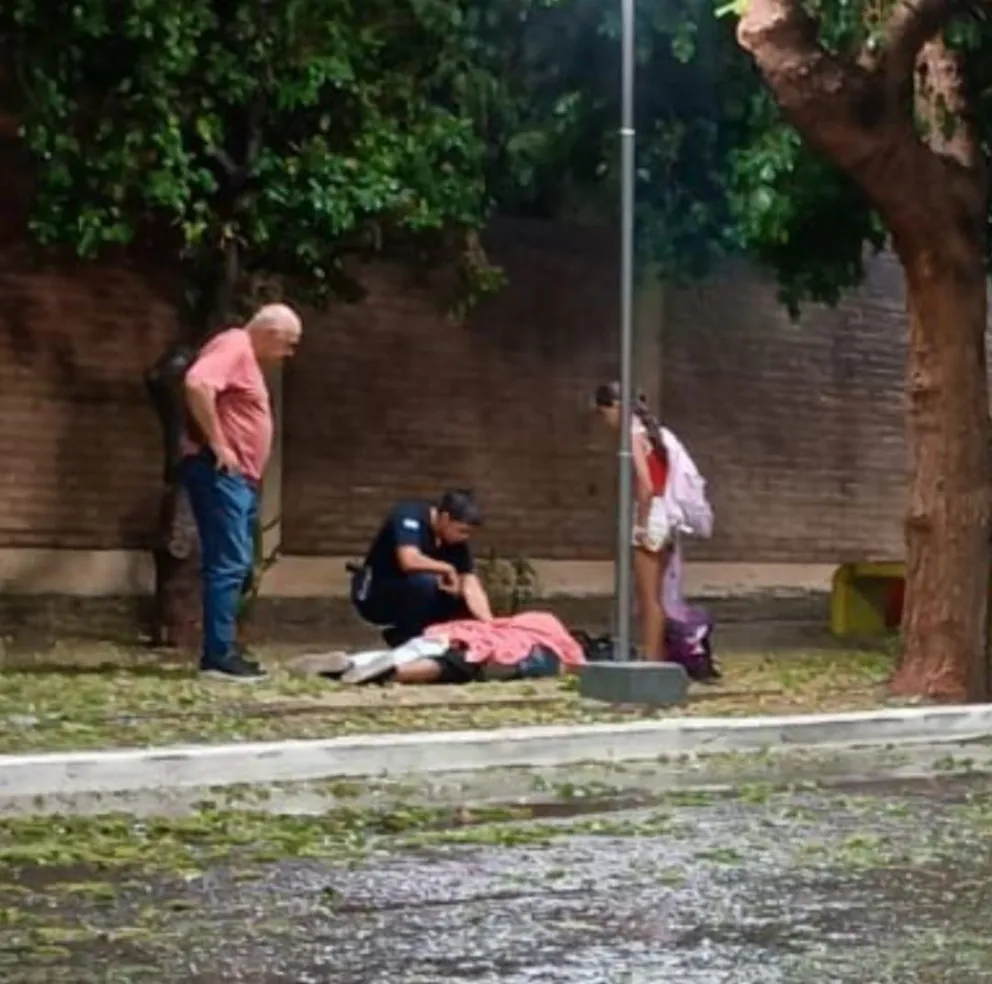 Cecilia Román, tendida en el piso, siendo asistida luego de la descarga eléctica que padeció al tocar una farola.